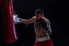 肌肉发达的英俊的拳击手给有力的向前踢练习轮拳击袋