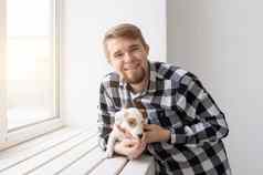 人宠物动物概念年轻的男人。拥抱小狗窗口白色背景