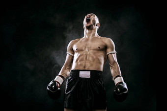 运动员泰拳泰国拳击手庆祝完美的胜利拳击笼子里孤立的黑色的背景烟复制空间