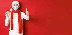 概念科维德圣诞节假期流感大流行快乐满意男人。圣诞老人他医疗面具显示翘拇指批准推荐手洗手液
