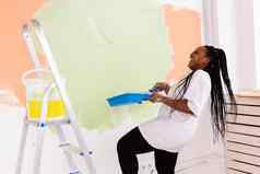 微笑非洲美国女人绘画室内墙首页改造修复重新装饰概念