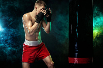 运动员男人。拳击手战斗手套拳击冲袋孤立的黑色的背景烟复制空间