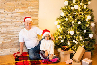 女孩祖父坐着地板上圣诞节女孩大父母生活房间圣诞节