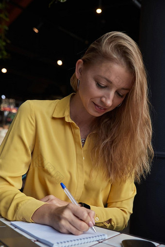 美丽的年轻的高加索人业务女人写作笔记笔记本咖啡馆