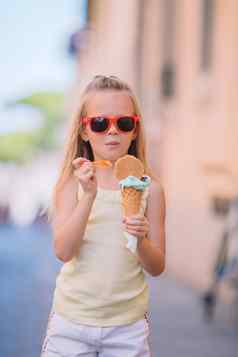可爱的女孩吃冰淇淋在户外夏天