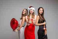 漂亮的年轻的女孩朋友节日礼服持有礼物红色的气球香槟庆祝假期灰色的背景