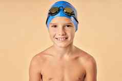 快乐的男孩游泳运动员站光橙色背景