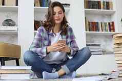 距离学习年轻的女学生检查社会媒体回来研究坐着地板上