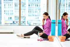 一边视图年轻的美丽的健身女人运动服装坐着地板上健身工作室健身房会说话的移动电话休息锻炼