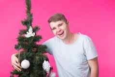 假期人概念快乐男人。圣诞节树粉红色的背景