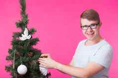 圣诞节假期概念肖像微笑男人。圣诞节树粉红色的背景