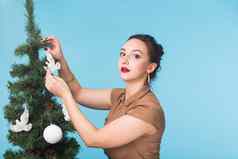 圣诞节假期人概念年轻的快乐女人装修圣诞节树蓝色的背景