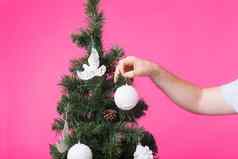 12月假期概念男人的手装修圣诞节树粉红色的背景