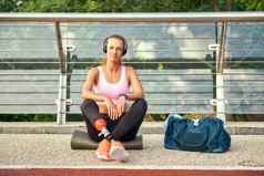 自信肖像年轻的女人体育服装耳机腿假肢坐着桥相机