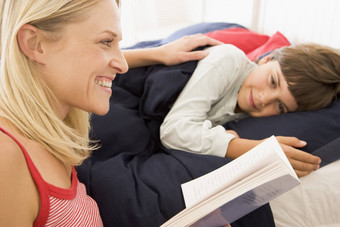 女人阅读书年轻的男孩床上微笑
