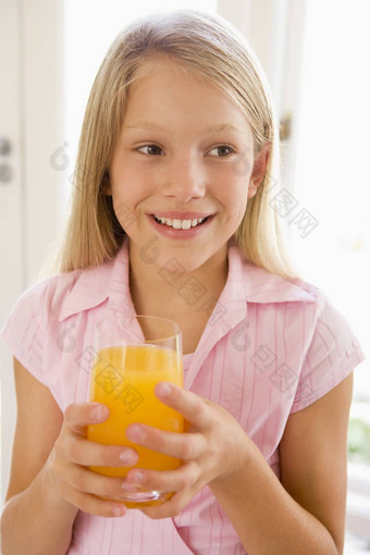 年轻的女孩在室内喝橙色<strong>汁</strong>微笑