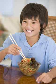 年轻的男孩餐厅房间吃中国人食物微笑