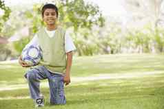 年轻的男孩在户外公园持有球微笑