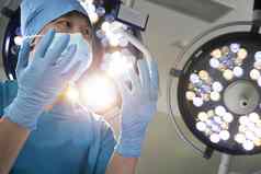 低角视图外科医生持有戴着手套手外科手术灯