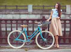 年轻的优雅穿着女人自行车夏天生活方式