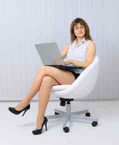 美丽的年轻的女人坐着椅子移动PC