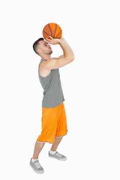 一边视图年轻的男人。扔篮球