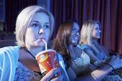 特写镜头年轻的女人喝软喝朋友看电影剧院