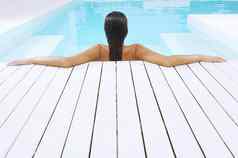 后视图年轻的女人游泳池休息在游泳池边