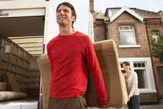 微笑年轻的夫妇卸货沙发卡车前面房子