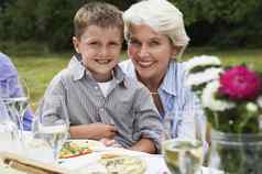 肖像快乐年轻的男孩祖母坐着餐厅表格花园
