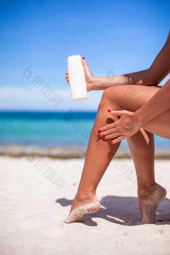 女人应用奶油光滑的晒黑腿热带beac