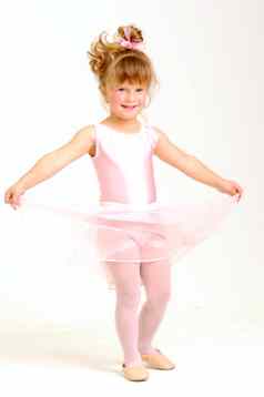 年轻的女孩穿粉红色的芭蕾舞衣服跳舞微笑