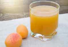 夏天喝新鲜水果杏汁玻璃杯成熟的杏子餐巾在户外阳光明媚的一天