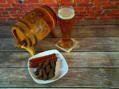 玻璃光啤酒板黑麦油炸面包丁大蒜烟熏巴伐利亚香肠木桶啤酒站木表格红色的砖墙特写镜头