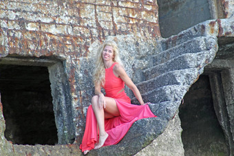 晒<strong>黑金</strong>发女郎女孩红色的衣服坐着石头废墟堡