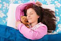 年轻的女人睡觉拥抱泰迪熊
