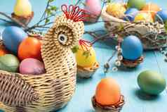 复活节作文柳条篮子形式鸡彩色的鸡蛋蓝色的木表格柳树树枝