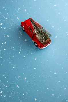 微型红色的车回来携带圣诞节树简单的blue-aquamarine背景雪前视图保存空间概念节日圣诞节情绪礼物交付趋势