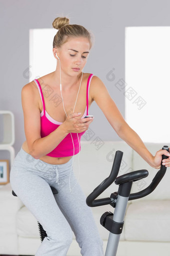 运动金发女郎培训锻炼自行车听音乐