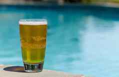 玻璃啤酒边缘在游泳池边