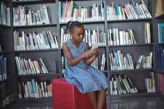 女孩移动电话坐着书架上图书馆
