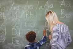 老师协助小学生写作字母黑板