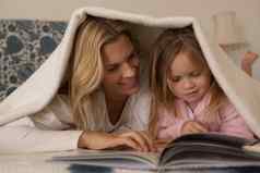 妈妈。女儿阅读故事书毯子卧室