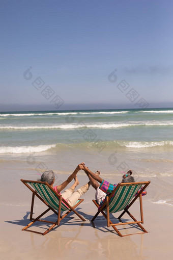 高级夫妇放松太阳懒人持有手海滩