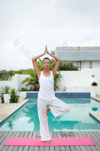 女人执行瑜伽游泳池后院
