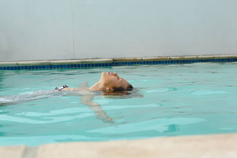 女人眼睛关闭浮动游泳池后院