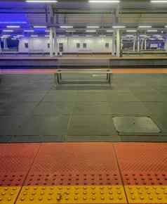 金属板凳上火车站色彩斑斓的灯红色的黄色的灰色的人行道上