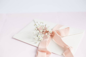 信封粉红色的背景桃子丝绸丝带粉红色的花婚礼邀请母亲的一天卡的地方文本复制空间