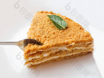白色板蜂蜜蛋糕美味的甜点酸奶油金属勺子咬蛋糕