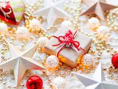 圣诞节一年明星装饰白色针织背景现在盒子包装工艺纸圣诞节树象征金属光灯泡精致的模式金珠子红色的球